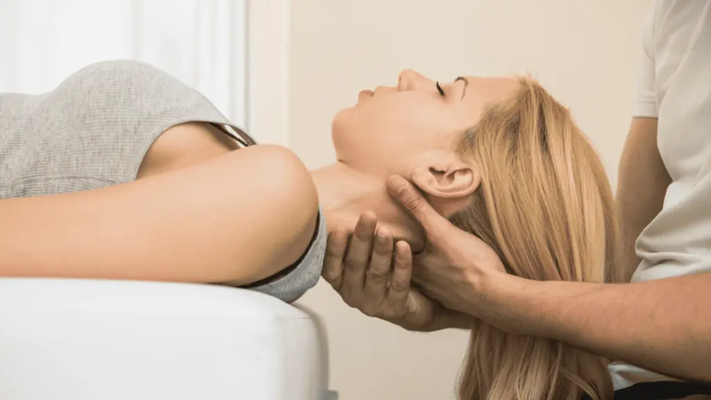 A chiropractor supporting a patient head while performing a neck adjustment on a treatment table