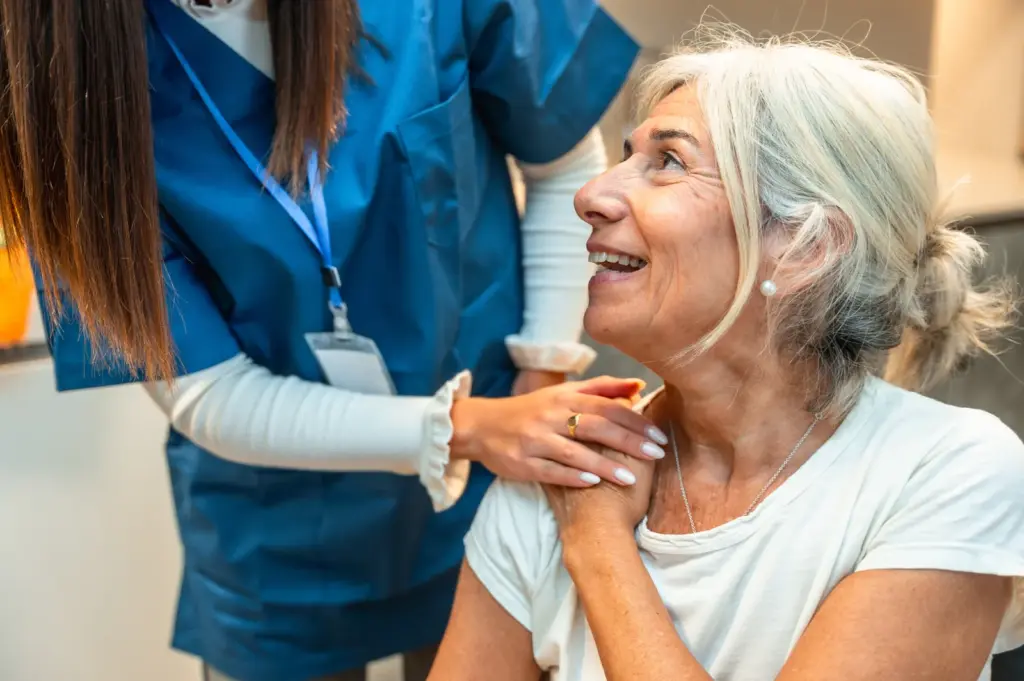 Clinician giving an injection into the upper arm of a seated patient