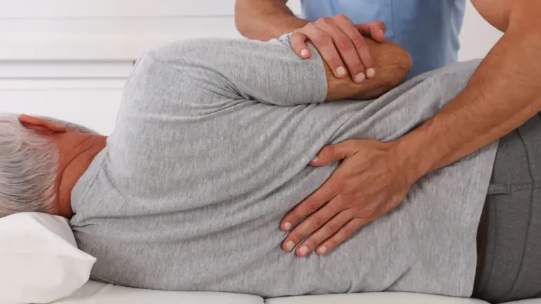 A chiropractor performing a side-lying lower back adjustment on an older patient