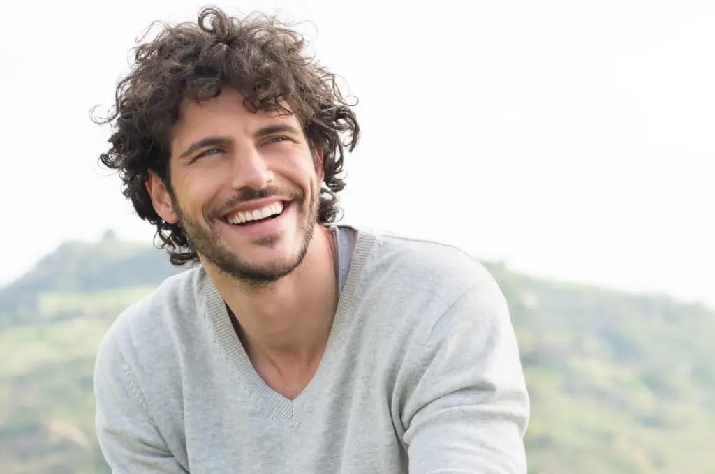 Man laughing outdoors with hills in the distance