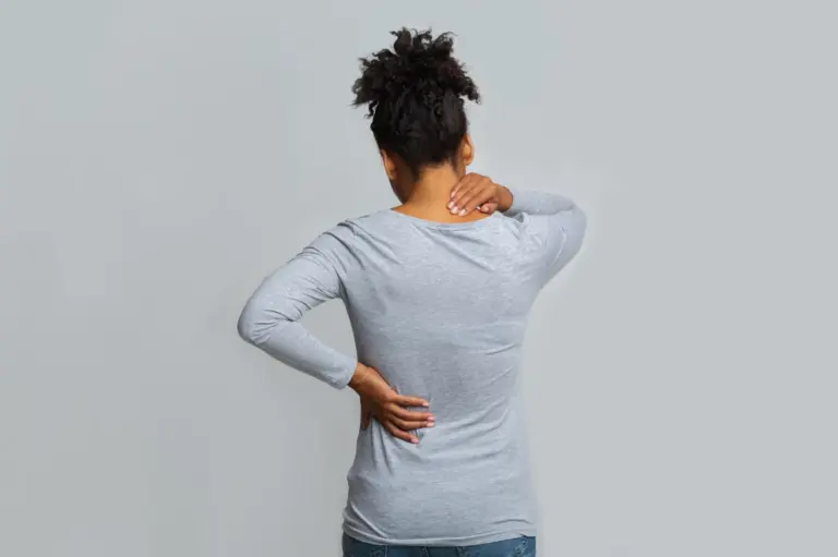 Woman standing with one hand on her neck and the other on her lower back