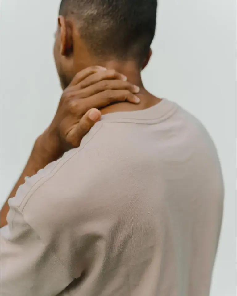 A man seen from behind resting his hand on the back of his neck
