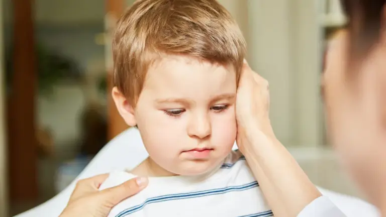 A young boy having the side of his head examined by a clinician
