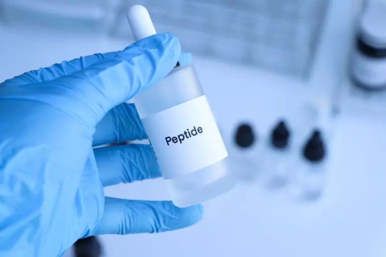 Gloved hand holding a small vial labelled Peptide in a laboratory