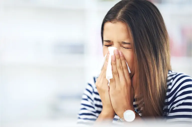 Woman sneezing into a tissue during allergy season