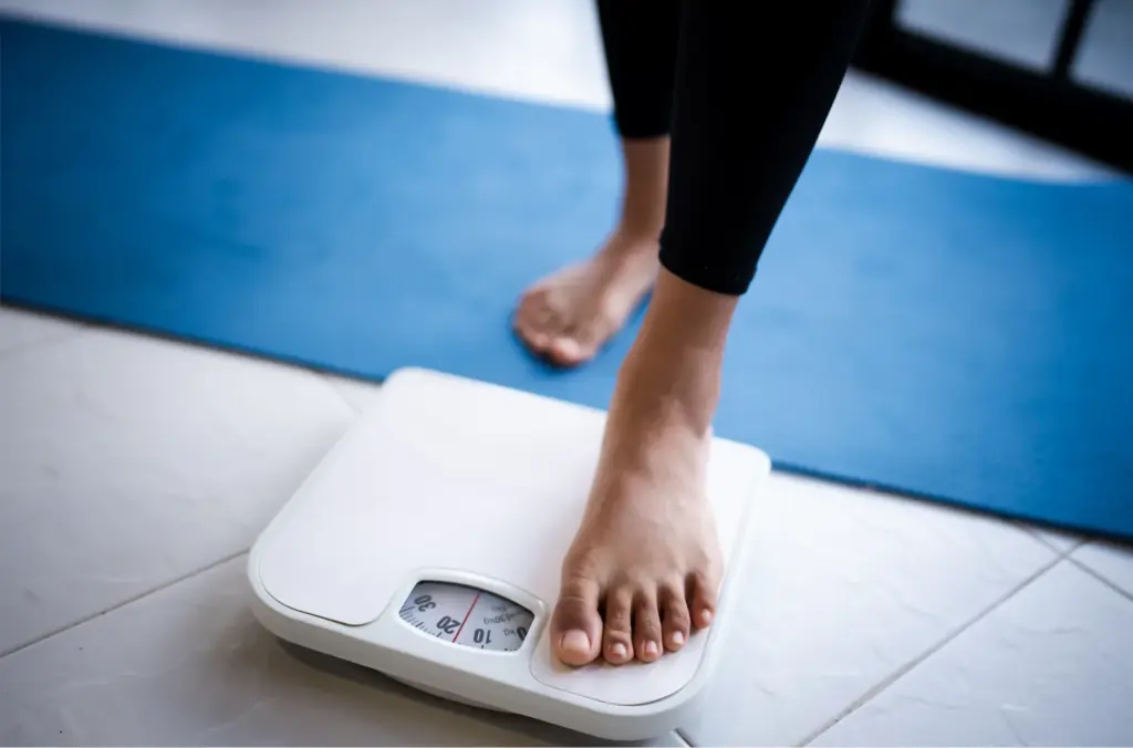Bare foot stepping onto a bathroom scale next to an exercise mat